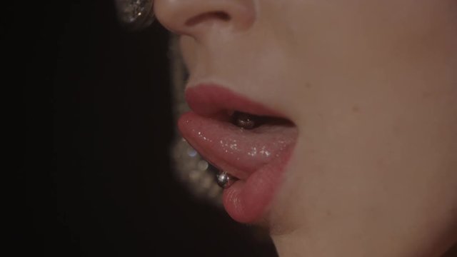 slow motion close-up of a beautiful woman sticking out her pierced tongue
