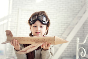 happy boy play with airplane in hand, child dreams about traveling by aeroplane