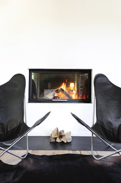 Design fireplace and chairs with cowhide carpet and logs for the fireplace in an old renovated chalet