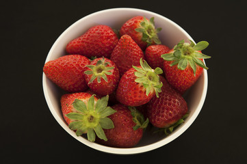Bowl of ripe strawberries with black background