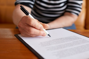 Old woman signature document and sitting behind desk