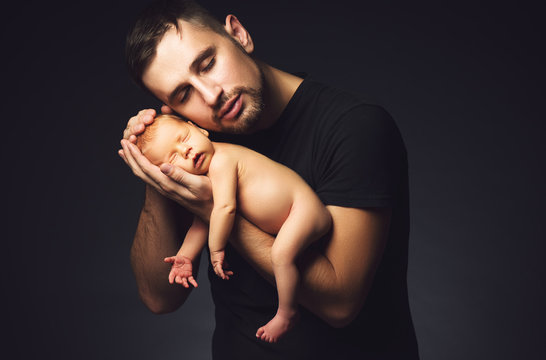 Newborn baby in his father's hands in dark