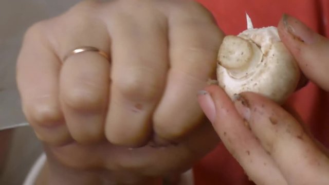 Female hands with a knife clean and cut mushrooms Champignons 