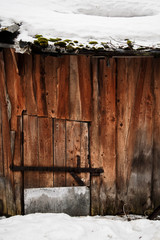 Wooden door of an old barn with a metal lock