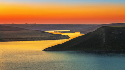 Magnificent sunset scenery on the Dniester canyon and curves river with colorful evening sky reflected in the water.