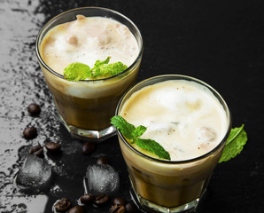 Ice coffee glasses with ice cubes and froth, mint leaves decor