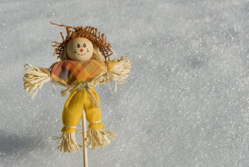 small straw scarecrow on a background of fresh snow, mountains, Italy
