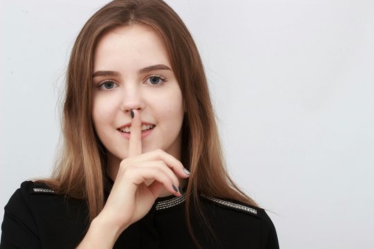 beautiful young girl holding finger near mouth isolated white background