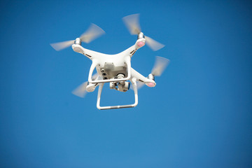 white drone hovering in a bright blue sky