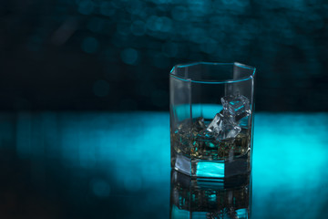 glass of whisky with ice on a blue background