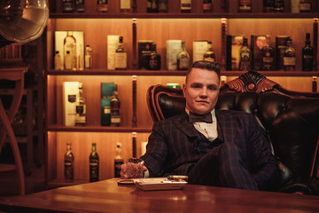 Confident upper class man with glass of beverage in gentlemen's club