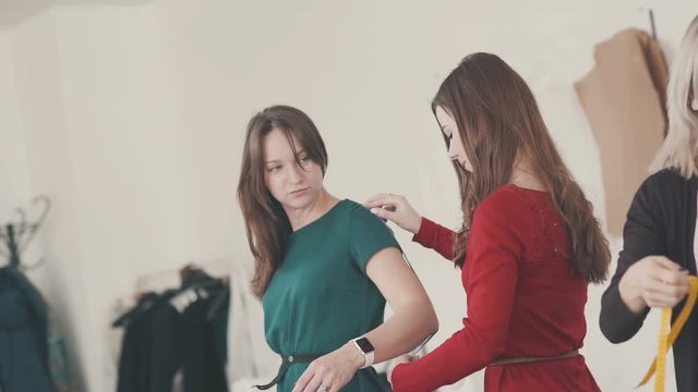 Close-up: The seamstress measures the length of the sleeve using a centimeter tape. Female fashion designer taking measurement with model. Tailor women taking measures shirt using tape meter