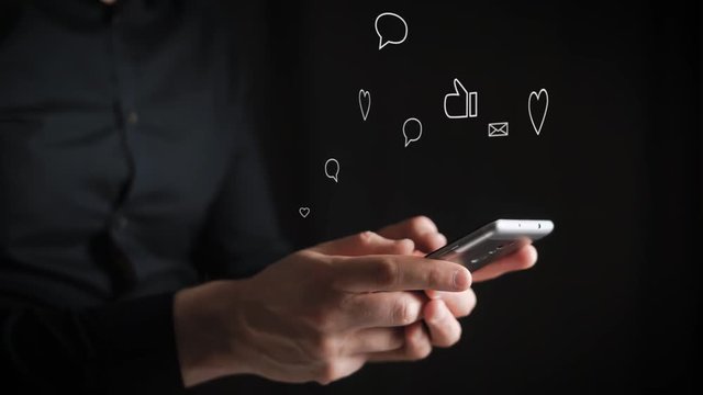 Concept, digital online life and social networks. A businessman in a shirt uses his smartphone to view his accounts. Animation shows likes, comments, subscriptions, reposts.