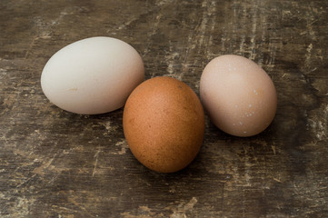 Three fresh chicken eggs on an old wooden background