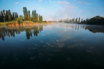 Fototapeta na wymiar Nuclear power plant at morning. Industrial landscape with lake and trees.