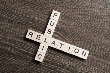 Public Relation crossword on office table collected of wooden cubes