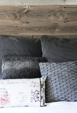 Headboard in old wood and gray cushions in a swiss chalet