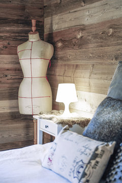 Cosy bedroom in an old wooden chalet with nightstand, fur, couturier's bust and cushions
