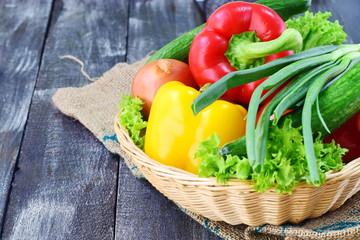Fresh vegatables: paprika, tomato, onion,onion, carrot on a rustic textile cloth on a grey wooden background. Healthy eating concept