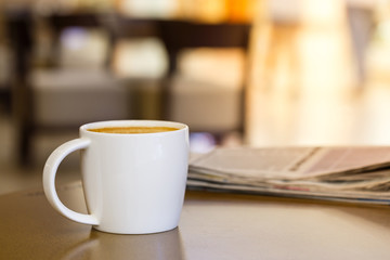 Cappuccino coffee cup on wooden table with newspaper