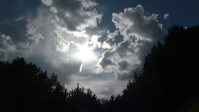 Sun shining as storm clouds pass over tree line in Portland, Oregon, real time.