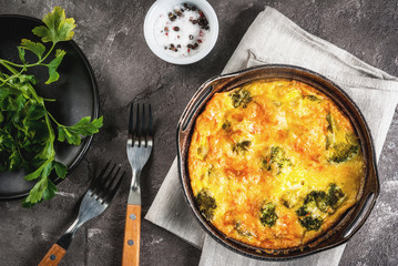 Traditional French food. quiche lorraine. Frittata. Baked in the oven egg omelet with vegetables - broccoli - cheese and greens. Rustic, homemade meal. On a gray concrete table