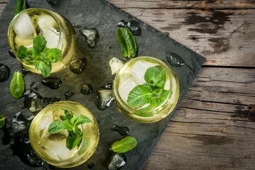 Tuinposter Traditional Spanish alcoholic drink, Rebujito cocktail - white wine, carbonated water (soda), mint, lemon juice. On a rustic wooden table, three glasses. Copy space © ricka_kinamoto