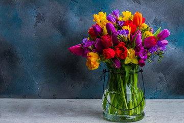 bouquet of bright spring flowers in vase on dark background with copy space