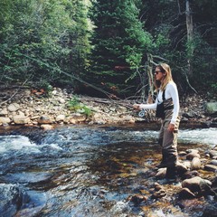 Young woman fly fishing along a Colorado stream