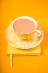 Cup and saucer and coffee with milk on a yellow background