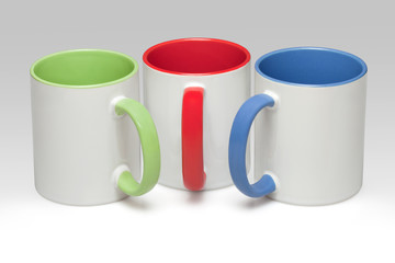 Three white mugs on a gray background