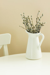 fresh willow catkins in metal pot on white table