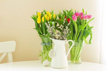fresh yellow and violet tulips and willow catkins in pot with easter eggs