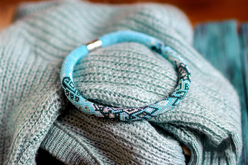 Fototapeta premium beautiful blue bracelet lies on a knitted scarf, female costume jewelry, gifts to girls
