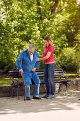 cheerful daughter helping disabled father in park.