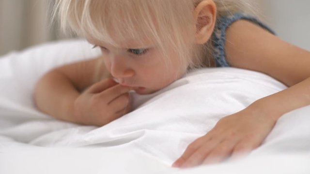 Little girl lying on the bed and playing games on smartphone slow motion