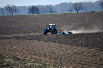 Fototapeta premium Track rollers with tractor prepares soil for planting spring crops