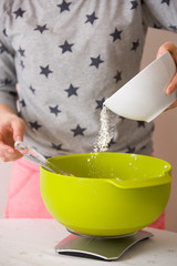 Woman making dough for muffins. Mixing flour, sugar, eggs and other ingredients from colorful bowls. Homemade food, baking at home.