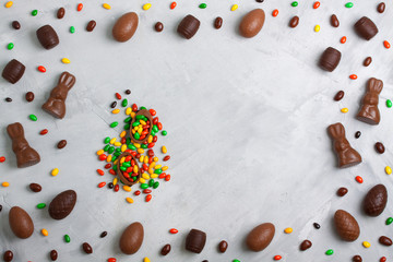 Chocolate easter eggs, rabbits, casks and sweets on concrete background