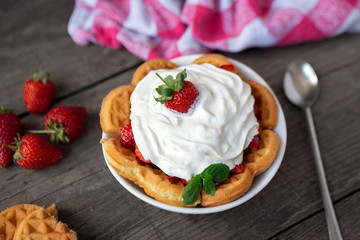 Fresh red strawberries and whipped cream on waffle.