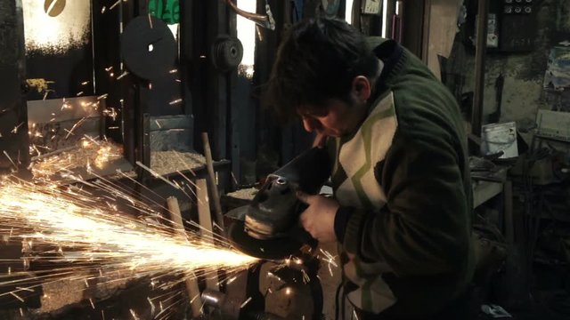Male worker handles iron ship grinder, slow motion
