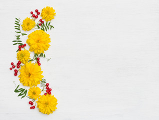 top view on beautiful yellow summer flowers on white wooden background.