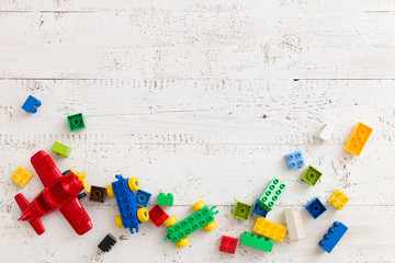 Top view on colorful toy bricks on a white wooden background. Toys in the table