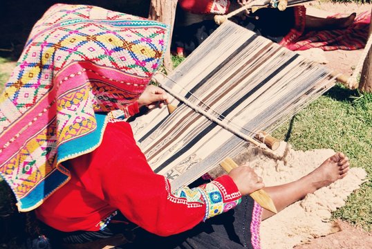 Peruvian woman sitting and weaving colorful textiles