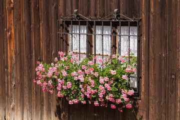 Fototapeta na wymiar Window and rough wooden walls with flowers in traditional wabi-sabi aesthetics