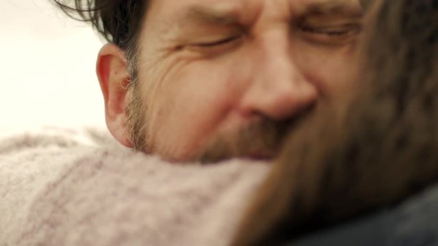Sad man in love hugging girlfriend crying slow motion closeup at sunset