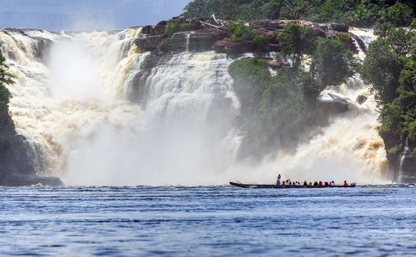 The powerful Golondrina falls and tourists boat in the lagoon of the Canaima national park - Venezuela, Latin America