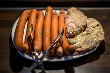 white plate with meat for grilling bbq Sausages, steak close up raw ready for fire
