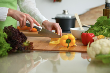 Closeup of human hands cooking vegetables salad in kitchen on the glass table with reflection. Healthy meal and vegetarian concept