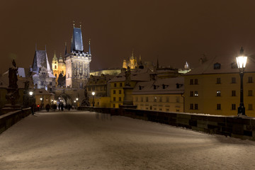 Obraz premium Night snowy Prague Lesser Town with Bridge Tower and St. Nicholas' Cathedral from Charles Bridge, Czech republic